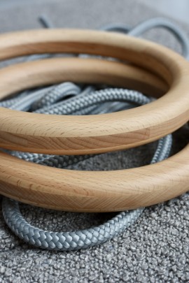 Zbliżenie na drewniane kółka gimnastyczne z litego drewna bukowego wraz z szarą liną