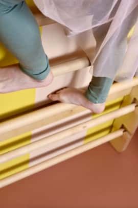 zbliżenie na bezpieczny system demontowalnych szczebelków drabinki gimnastycznej Nuki FunActive z widocznymi stopami dziecka