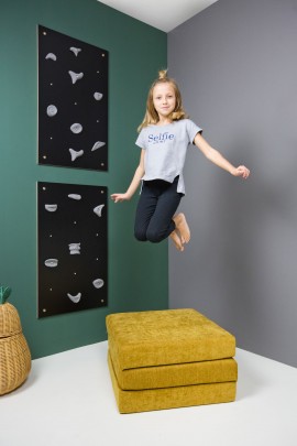 podskakująca dziewczynka przy ścianę wspinaczkowej Nuki w kolorze czarnym i obok miodowego materaca Sfera