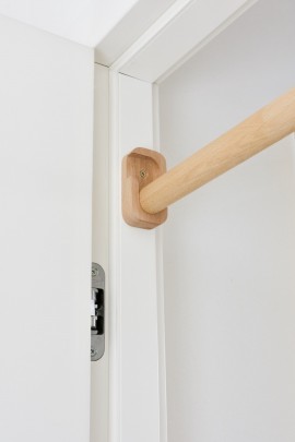 Drewniany drążek do podciągania Nuki FunActive zamontowany w białej futrynie drzwi