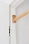 Drewniany drążek do podciągania Nuki FunActive zamontowany w białej futrynie drzwi